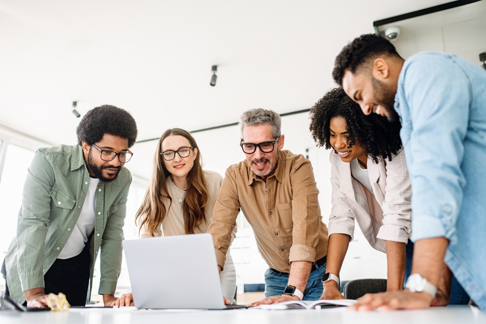 A,Group,Of,Diverse,Professionals,Is,Standing,Around,A,Laptop,
